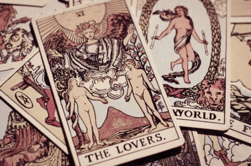 The Lovers tarot card lays upwards on top of a pile of other cards